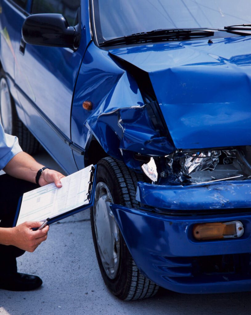 Surveyor at a blue damaged car after an accident